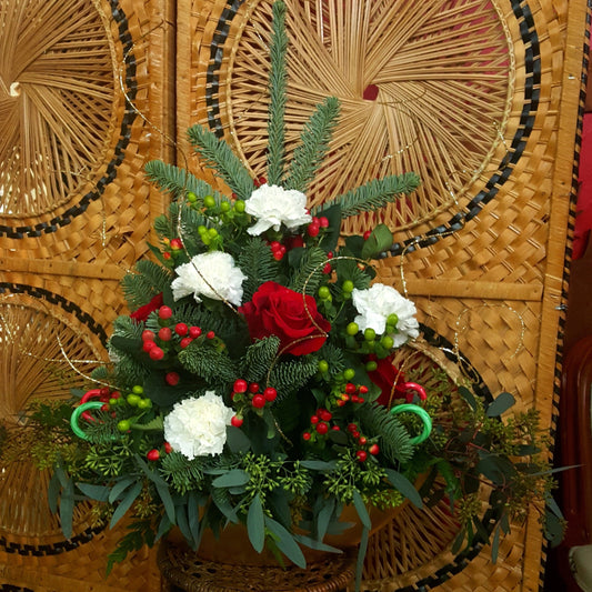 A festive flower arrangement resembling a pine tree, featuring a mix of pine branches, eucalyptus, roses, carnations, hypericum berries, candy canes, and silver sticks