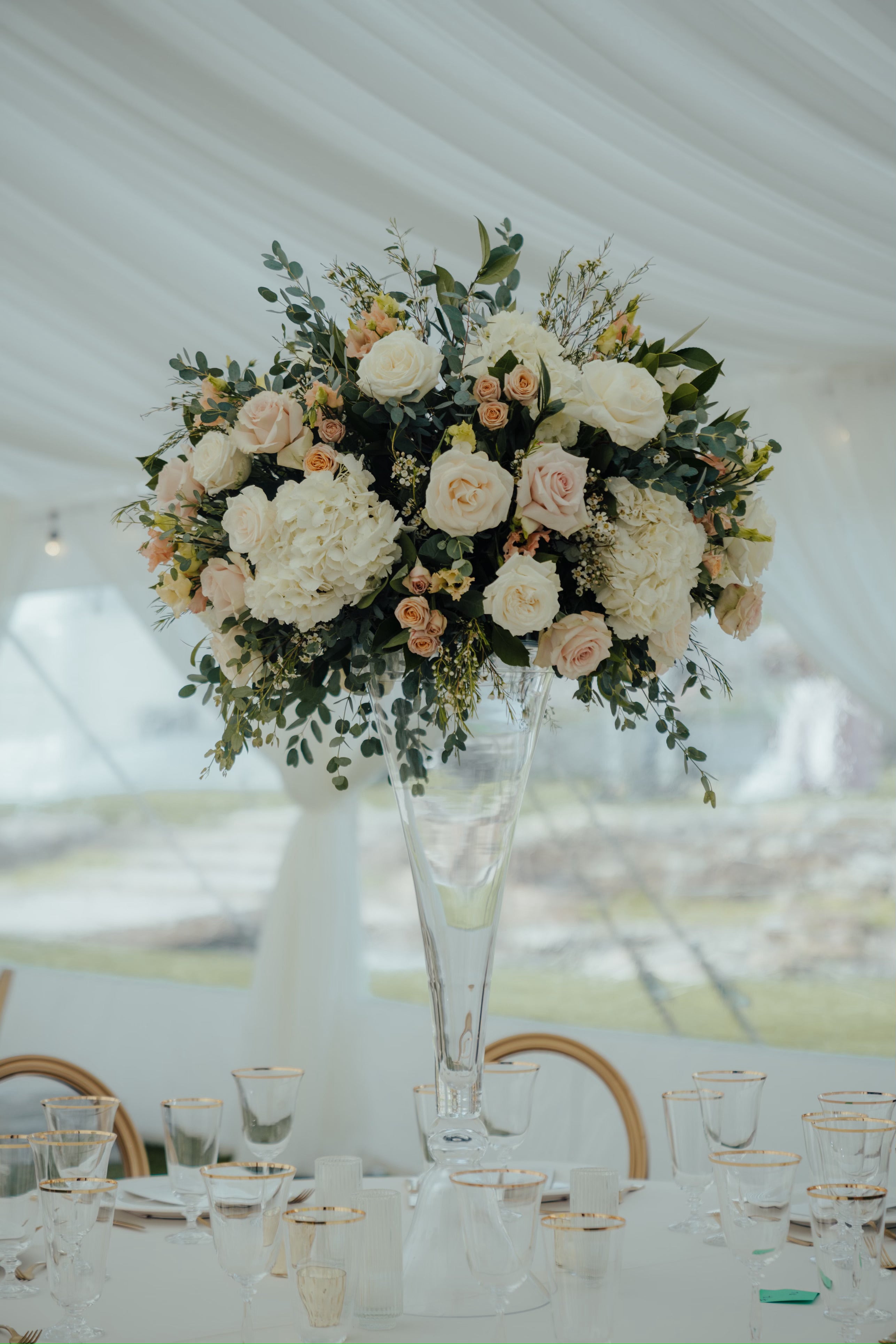 Stunning wedding centerpiece featuring flowers in a tall, trumpet-shaped glass vase