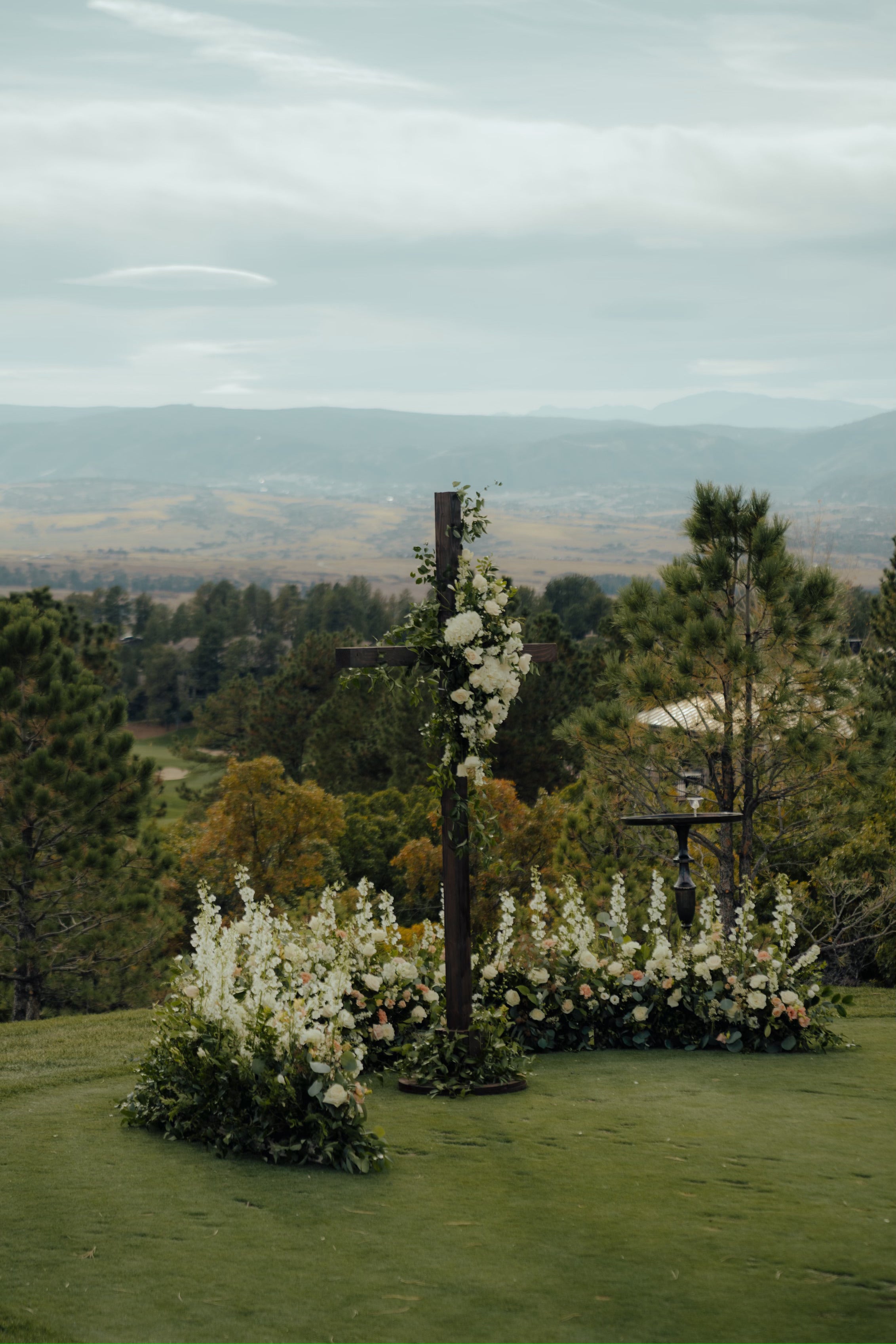 A wedding ceremony on a golf course adorned with beautiful wedding flowers and a cross placed in the middle.