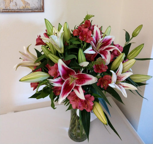 A beautifully elegant bouquet featuring stargazer or rubrum lilies as a focal. The beautiful starshaped lilies are partenered with stunning pink alstromeria and kimberly fern. Presented in a clear glass vase. 