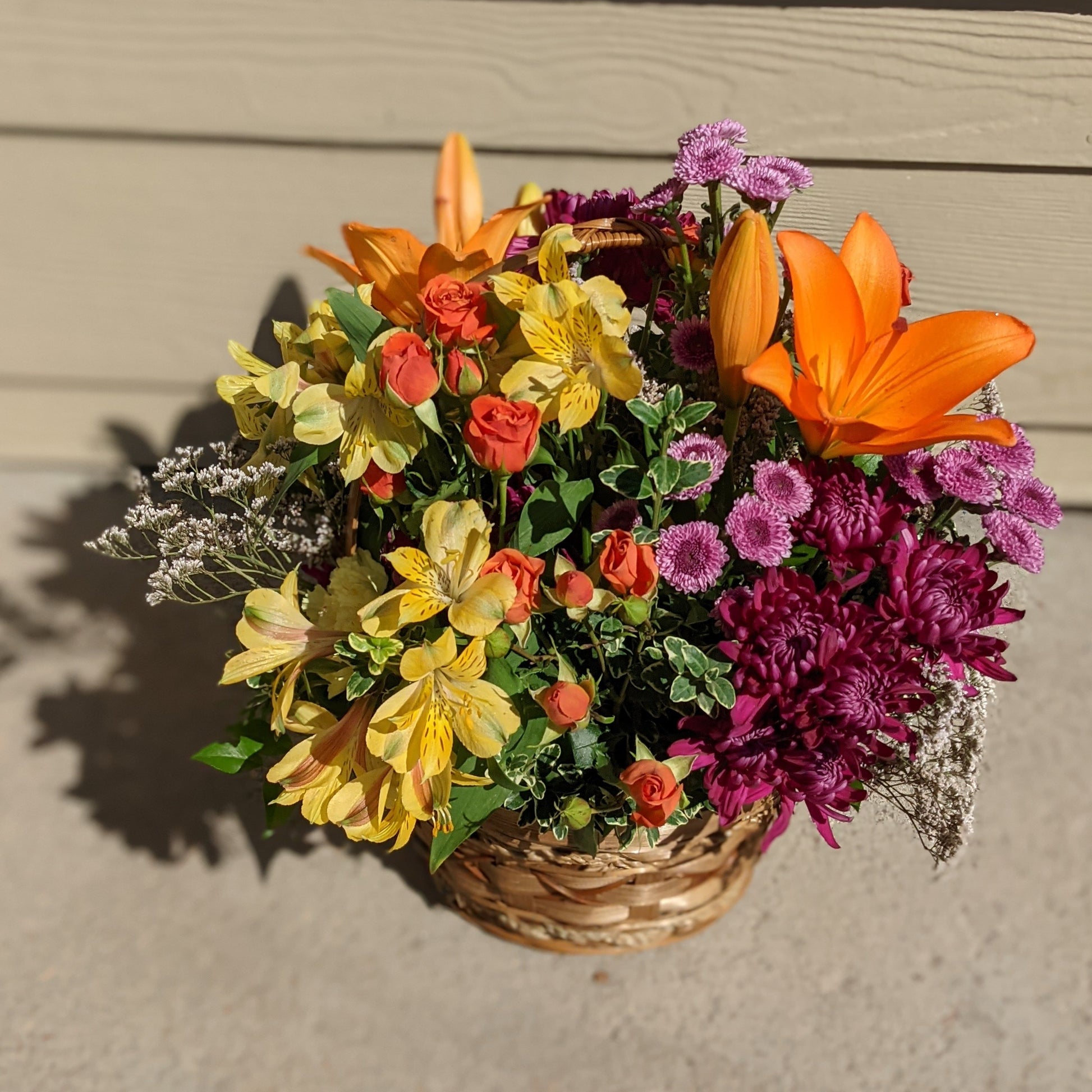 Basket of mixed fresh flowers. This photo has flowers like alstromeria, spray roses, mums, buttons, and lilies. 