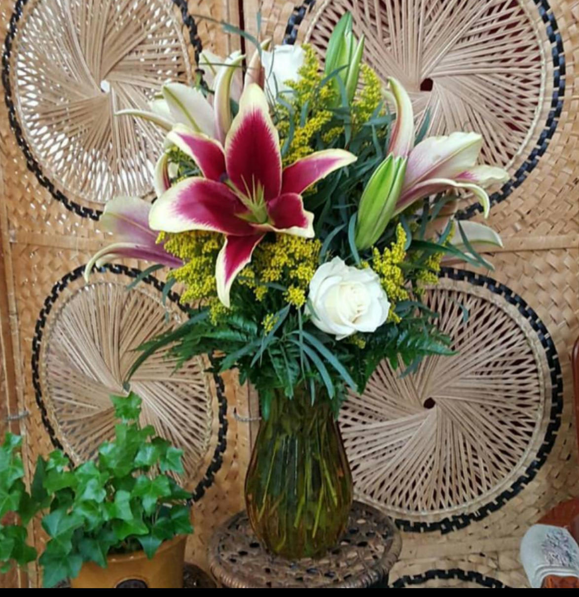 A beautifully elegant bouquet featuring african lady lilies as a focal. The beautiful starshaped lilies are partenered with lovely white roses, yellow solidago, feather eucalyptus and leather leaf fern.. Presented in a yellow glass vase. 